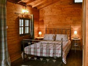 una camera con un letto in una baita di tronchi di The Sunset Cabin a Beccles