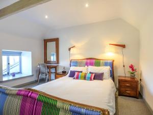 a bedroom with a large bed with colorful pillows at The Cow Shed in Buckland St Mary