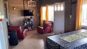 Habitación con sillas rojas, mesa y TV. en Cabaña Las Calandrias in 