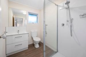 ein weißes Badezimmer mit Toilette und Dusche in der Unterkunft The White House - Taupo Holiday Home in Taupo + 14 Fotos