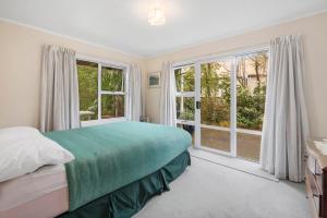ein Schlafzimmer mit Bett und großen Fenstern in der Unterkunft The White House - Taupo Holiday Home in Taupo