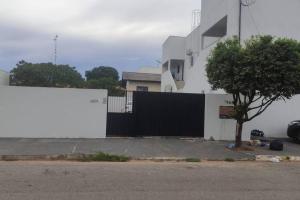 a white building with a black fence and a tree at Apartamento Sorriso in Sorriso