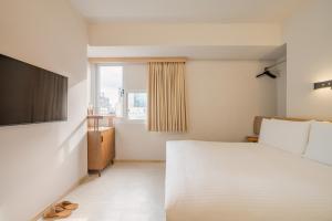 a bedroom with a large white bed and a window at Inns Hotel in Kaohsiung