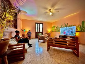 un uomo seduto su un divano in un soggiorno con TV di Hostal Central Oaxaca a Città di Oaxaca