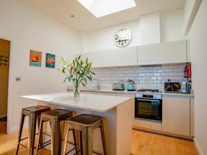 a kitchen with a island with two stools and a clock at Penthouse 47 Zinc in Newquay