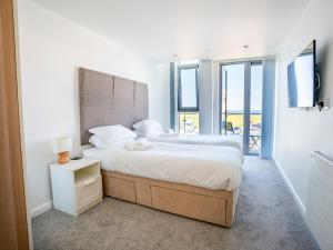 a white bedroom with a large bed and a window at Penthouse 47 Zinc in Newquay