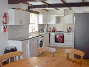 a kitchen with white cabinets and a table and chairs at Captains Cottage - E3643 in Whitby
