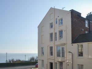 een wit gebouw met de oceaan op de achtergrond bij Sunnyside in Filey