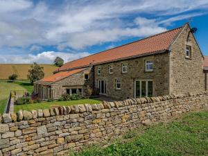 a brick house with a stone wall next to it at Turnip Cottage in Newsham
