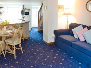 a living room with a blue couch and a table at Hobbits in Marazion