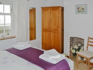 a bedroom with a bed and a wooden cabinet at Hobbits in Marazion