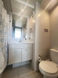 a white bathroom with a toilet and a sink at Apartamento General Mackenna B&E in Santiago