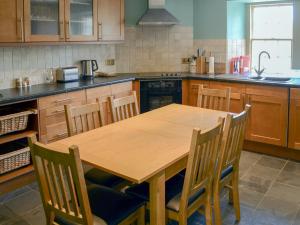 eine Küche mit einem Holztisch und einigen Stühlen in der Unterkunft Tressady Coach House in West Langwell