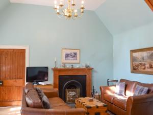 a living room with a couch and a fireplace at Tressady Coach House in West Langwell