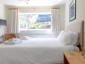 a bedroom with a large white bed with a window at Rockvale 1 in Salcombe
