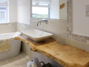 a bathroom with a sink on a wooden counter at Rhunahaorine Cottage in Gortinanane