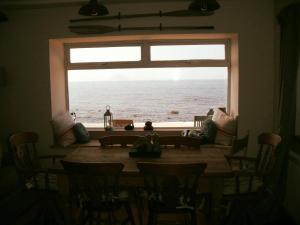 a dining room table with a window looking out at the ocean at Gull Cottage in Lendalfoot
