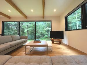 a living room with a couch and a tv at SEVEN TREES BY AOKIKO in Omachi