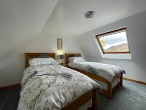 two beds in a room with a window at Lag Cottage in Dornie