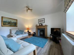 a living room with a white couch and a fireplace at Lag Cottage in Dornie