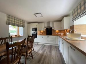 a kitchen with white cabinets and a table and chairs at Lag Cottage in Dornie