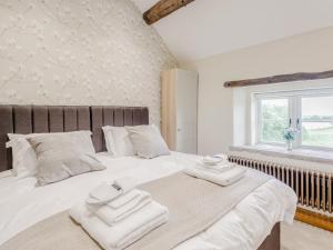 a bedroom with a large white bed with towels on it at Alton Hall Cottage in Ashover