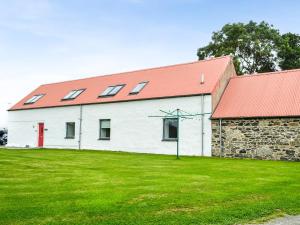 a white building with a red roof and a grass field at The Barn - Uk33396 in Isle of Gigha
