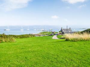 a green grassy field with boats in the water at The Barn - Uk33396 in Isle of Gigha