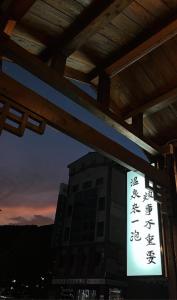 un panneau devant un bâtiment la nuit dans l'établissement 一口井溫泉 One Well Hot Spring, à Jiaoxi
