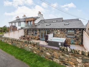 a stone house with a swimming pool in front of it at Seascape in Holyhead