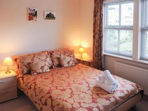 a bedroom with a bed and two lamps and a window at Darling Cottage in Bamburgh