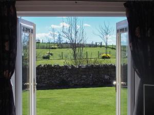 an open door to a yard with a stone wall at Darling Cottage in Bamburgh