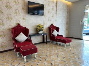 Cette chambre dispose de 2 chaises rouges et d'une télévision. dans l'établissement Fortune Hotel, à Johor Bahru