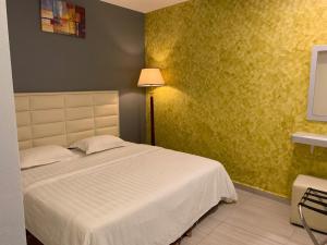 1 dormitorio con cama blanca y pared amarilla en Fortune Hotel en Johor Bahru