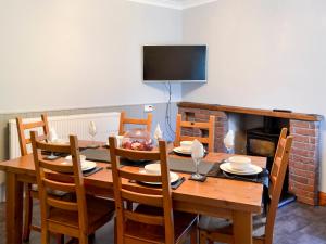 Butterhole Farmhouse في Kelton: غرفة طعام مع طاولة وكراسي خشبية