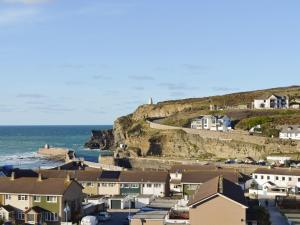 a village with houses and the ocean in the background at Seagull Cottage in Portreath