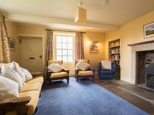 a living room with a couch and chairs and a fireplace at Sundial Cottage in Gammersgill