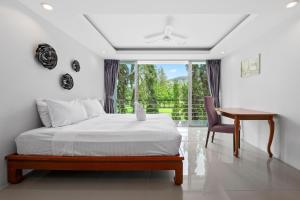 1 dormitorio con cama, escritorio y ventana en 4 bedrooms & bathroom for up to 12 guests 7kms to Patong beach at The Fairways golf villas en Phuket