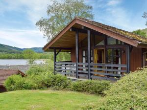 a small house with a porch and a lake at Loch Earn View Lodge in Lochearnhead