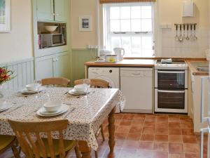 a kitchen with a table and chairs and a kitchen with white appliances at Lighthouse Cottage in Happisburgh