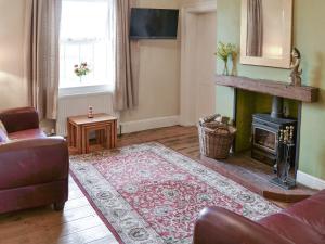 a living room with a couch and a fireplace at Lighthouse Cottage in Happisburgh
