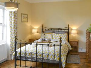 a bedroom with a bed with a yellow and white bedspread at Lighthouse Cottage in Happisburgh