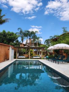a pool with chairs and umbrellas next to a house at Confraria da Prata Flats in Pirenópolis