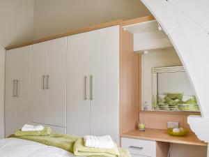 a bedroom with a bed with white cabinets and a mirror at White Sands in Criccieth