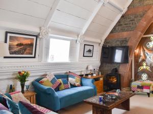 a living room with a blue couch and a tv at White Sands in Criccieth