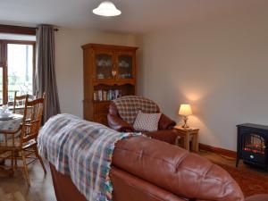 a living room with a leather couch and a chair at Trefechan in Pumpsaint