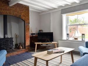 a living room with a couch and a table and a fireplace at September Cottage in Wells next the Sea