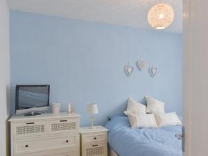 a blue bedroom with a bed and a tv at Britannia Way in Westward Ho