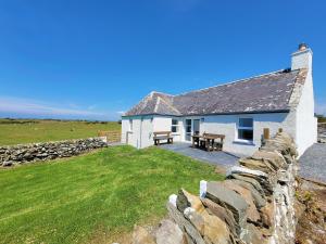 a white cottage with a stone wall and a picnic table at Garrarie Cottage in Monreith