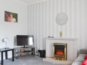 a living room with a fireplace and a tv at Hillside - Uk32930 in Gairloch